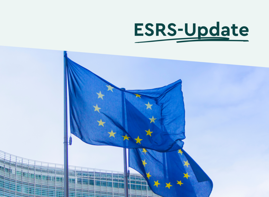 esrs update-artikel Bild zweier blauer EU-Flaggen vor einem Gebäude und Himmel. Darüber steht: ESRS UPdate